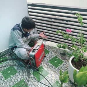 Kỹ thuật viên đang thông tắc thoát sàn nhà tắm bằng thiết bị chuyên dụng